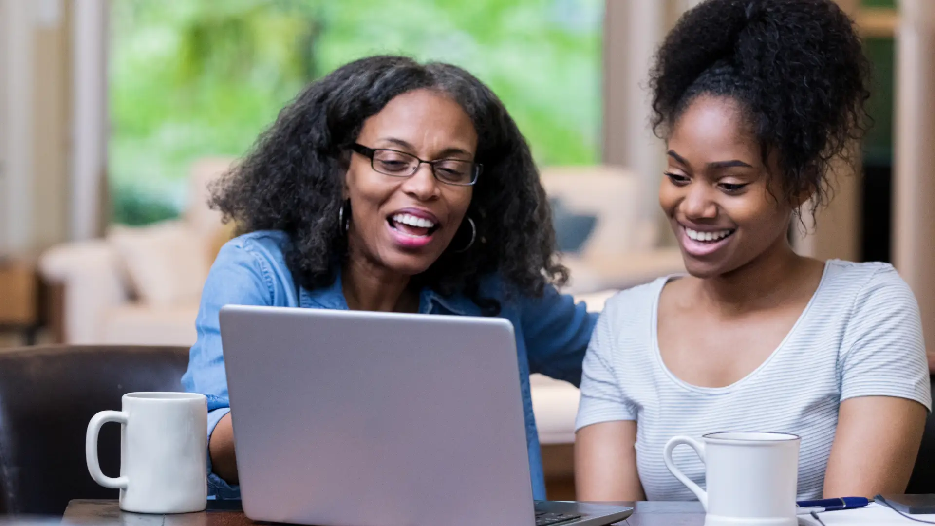 retired mother showing her daughter something on her laptop
