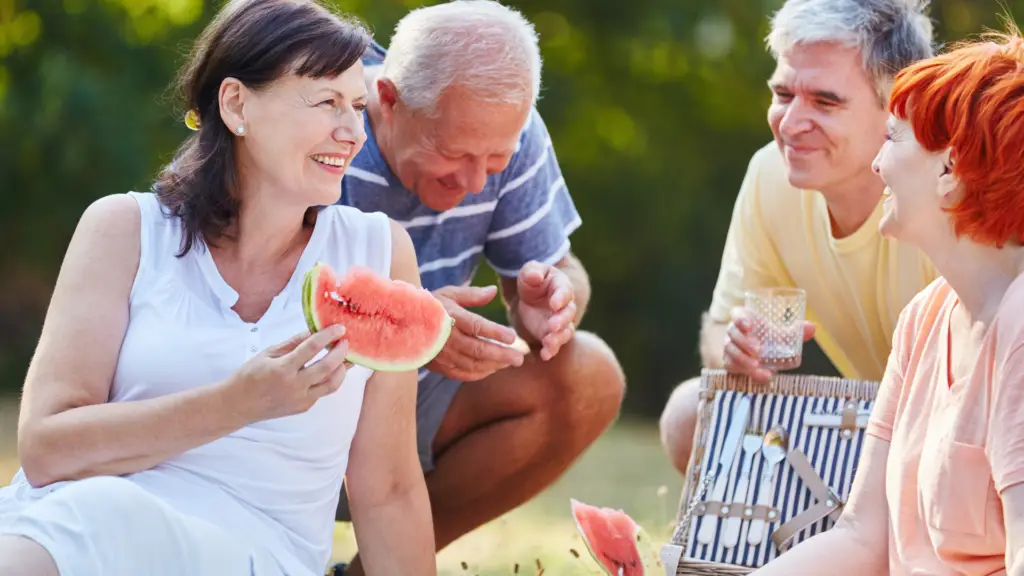 medicare age friends having a picnic and eating watermelon
