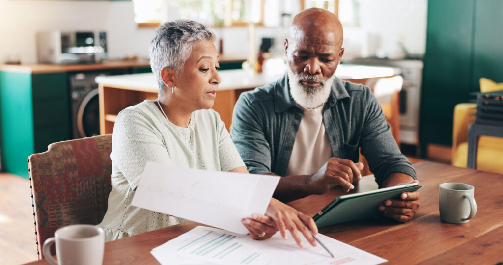 Older couple applying for Medicare online and reviewing enrollment paperwork.