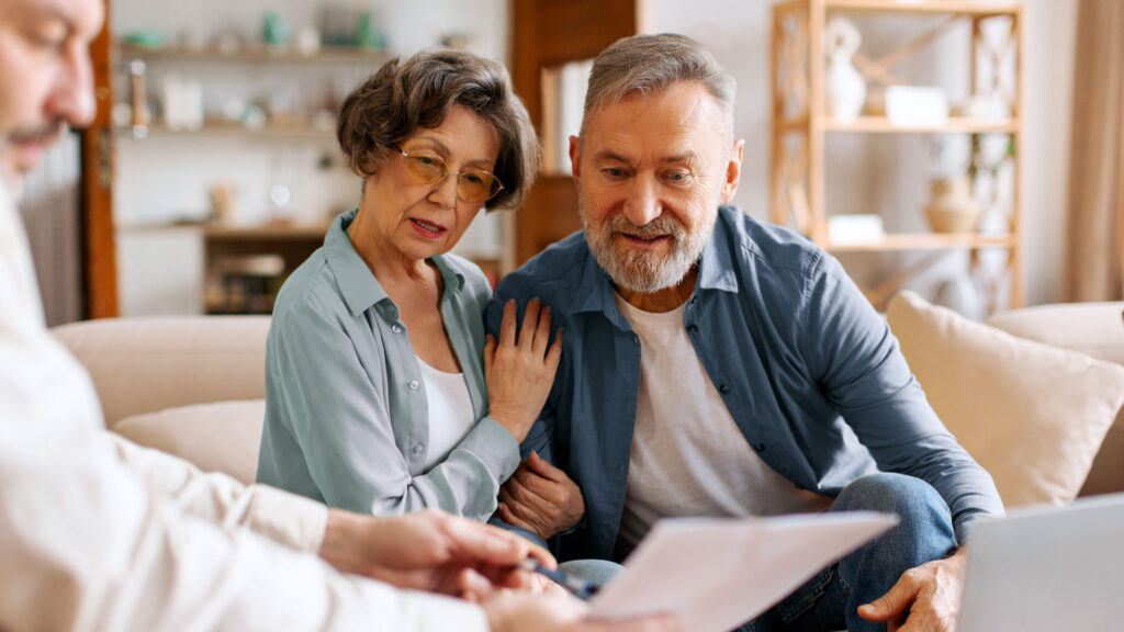 Older couple reviewing Medicare and auto insurance paperwork with an advisor in Michigan