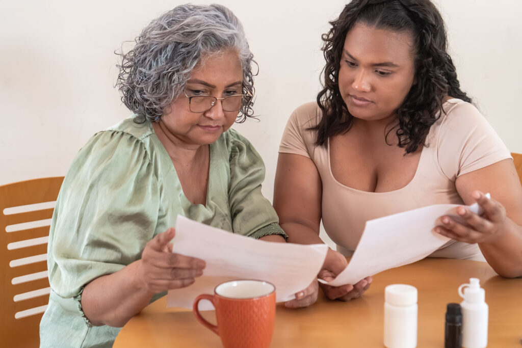 Older woman reviewing Medicare Part D prescription drug plan paperwork with a family member