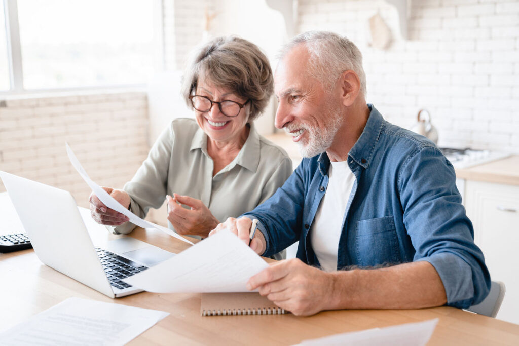 Senior couple reviewing Medicare plan information and paperwork on a laptop in Michigan.