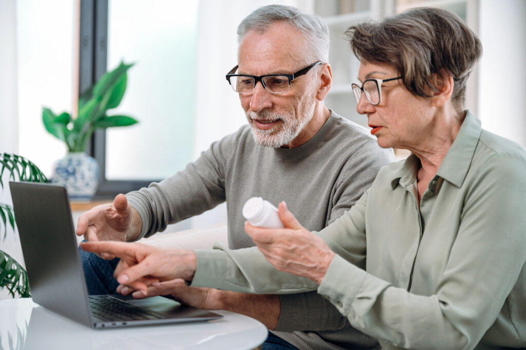 Senior couple reviewing Medicare Part D prescription drug coverage and medications on a laptop.